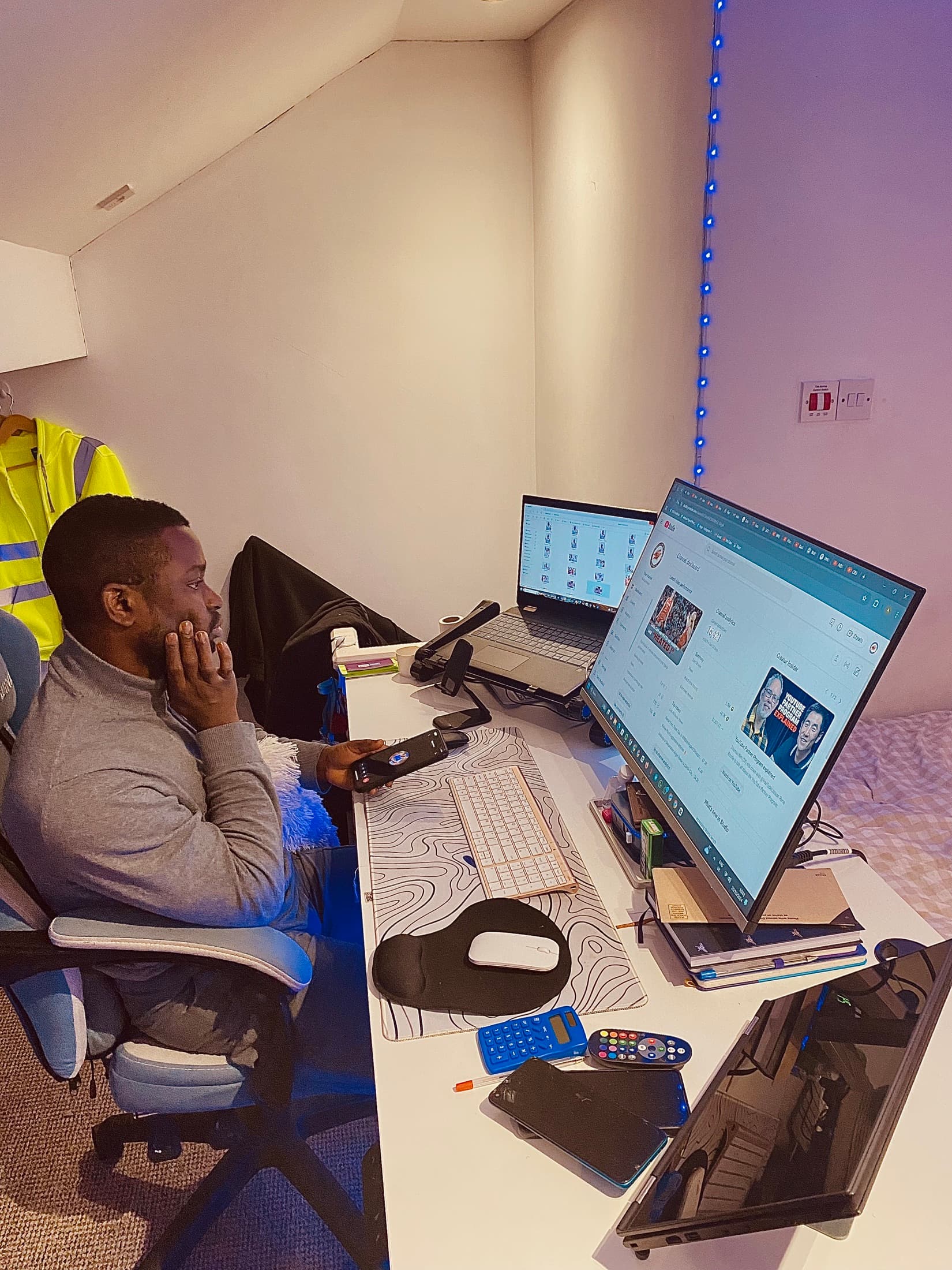 Oluwatobi Elijah at his desk with a YouTube channel dashboard on screen