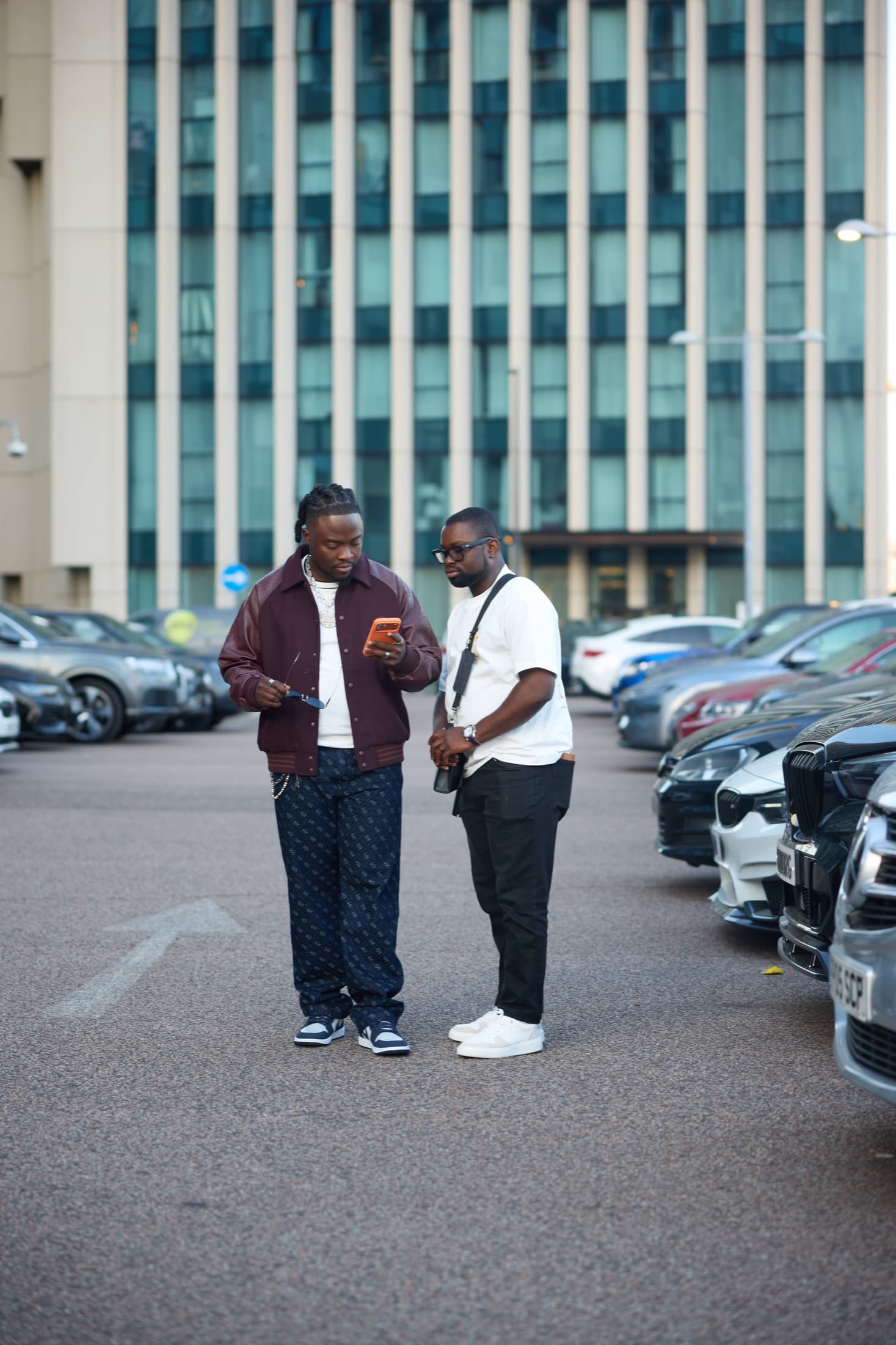 Oluwatobi Elijah with King Kaly in a car park, King Kaly checking his phone